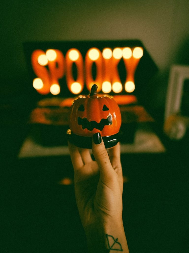 a hand holding a carved pumpkin