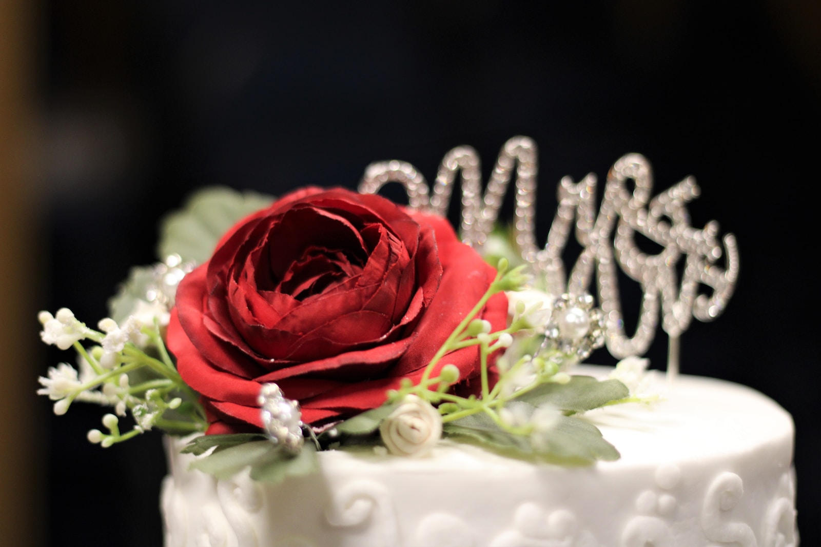 a close up of a cake with a red rose on top